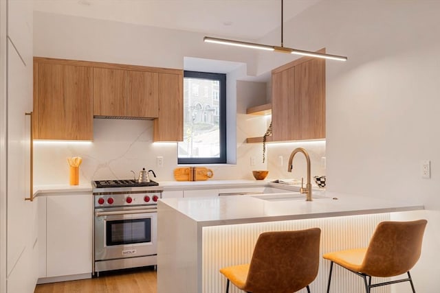 kitchen featuring open shelves, light countertops, premium range, a sink, and a peninsula