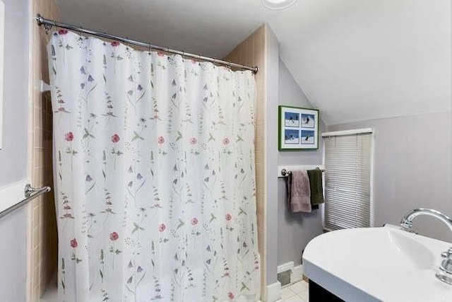bathroom featuring baseboards, a sink, vaulted ceiling, and a shower with curtain