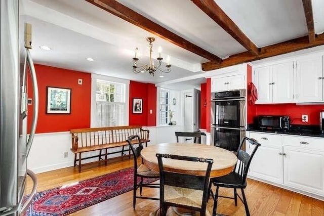 dining room featuring light wood-style floors, beam ceiling, and a chandelier