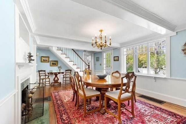 dining space with visible vents, crown molding, wood finished floors, stairway, and a chandelier