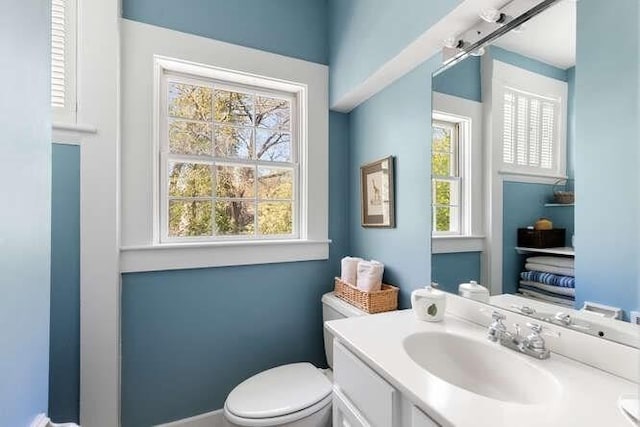 half bath with vanity, baseboards, and toilet