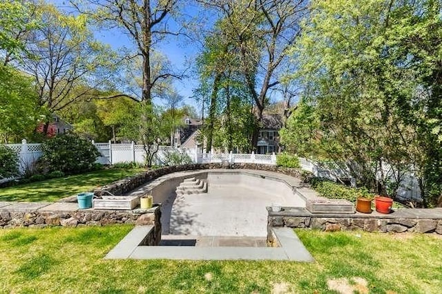 view of home's community with fence and a lawn