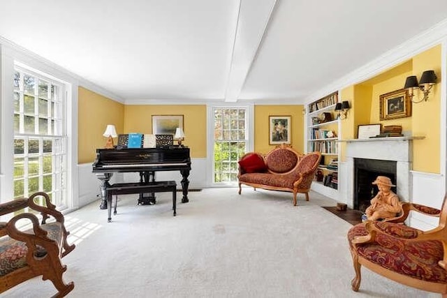sitting room featuring a fireplace with flush hearth, beamed ceiling, crown molding, and carpet