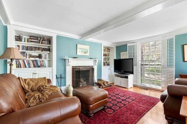 living area with crown molding, built in shelves, beam ceiling, and a fireplace