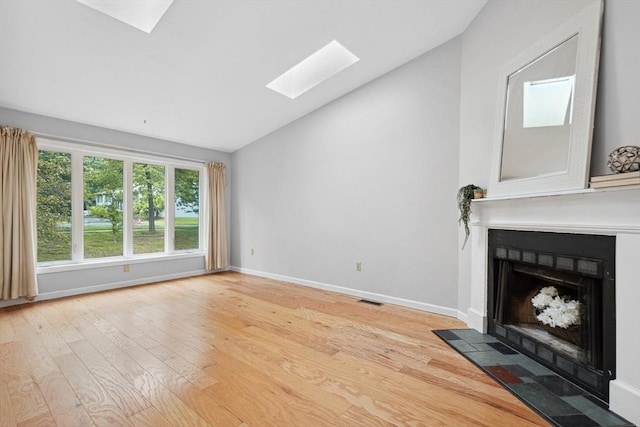 51 Nottingham Rd Unit 51, Grafton, MA 01519 - unfurnished living room featuring a skylight, vaulted ceiling, a fireplace with flush hearth, and light wood finished floors