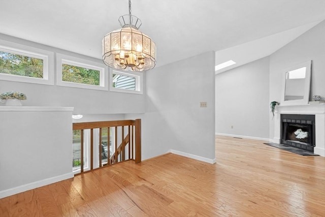 51 Nottingham Rd Unit 51, Grafton, MA 01519 - unfurnished living room featuring a chandelier, wood finished floors, a fireplace with raised hearth, and vaulted ceiling