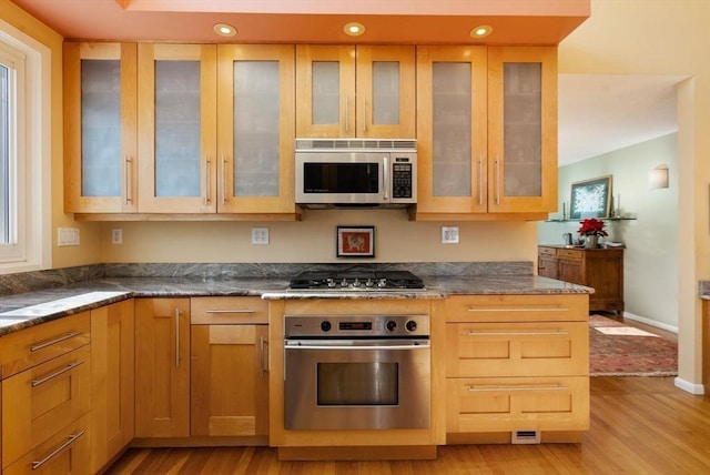 kitchen featuring glass insert cabinets, light wood-style floors, and stainless steel appliances