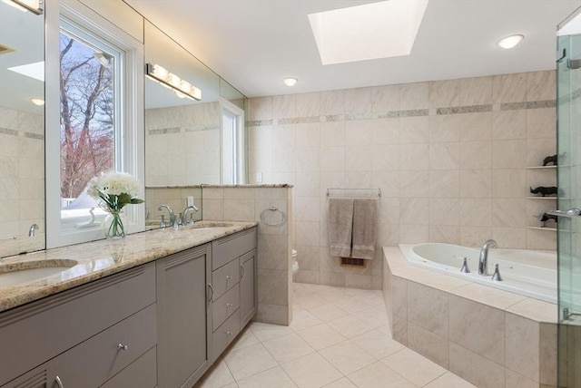 full bathroom featuring double vanity, a sink, tile walls, a bath, and tile patterned floors