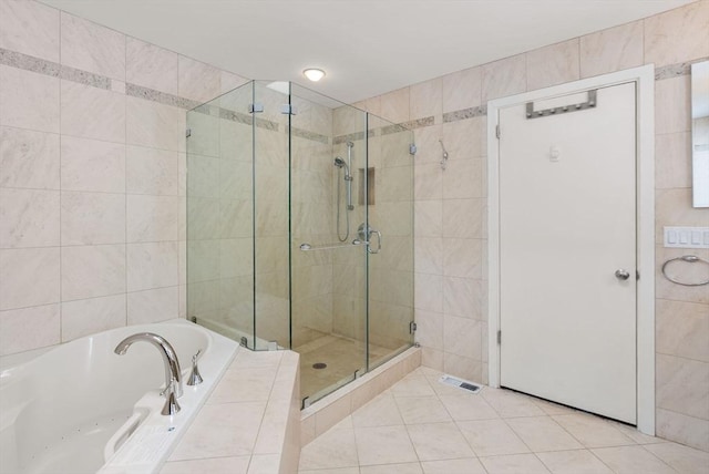 full bath with tile patterned flooring, a shower stall, and tile walls