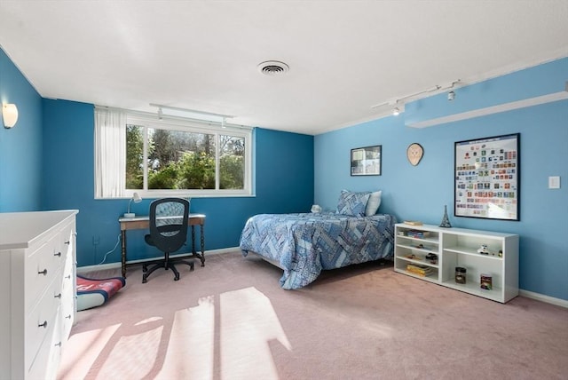 bedroom with light carpet, visible vents, track lighting, and baseboards