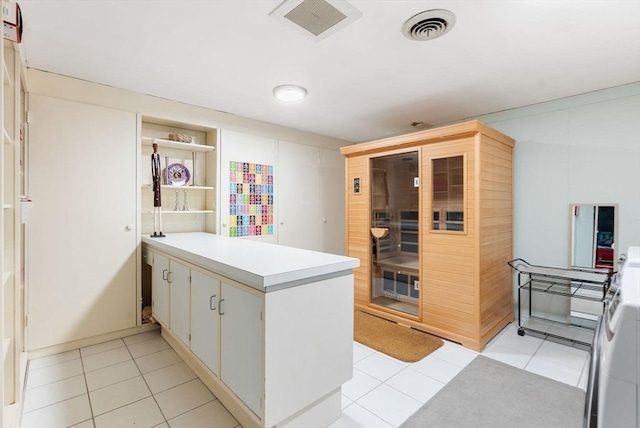 kitchen featuring visible vents, a peninsula, light tile patterned flooring, and light countertops