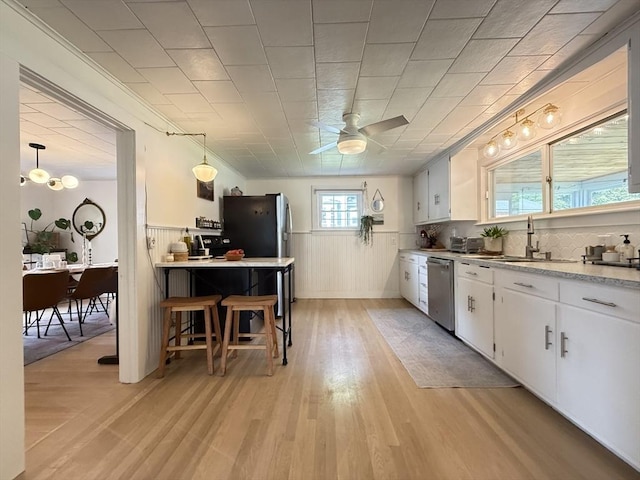 12 Wellington St, Buckland, MA 01370 - kitchen featuring stainless steel dishwasher, a sink, wainscoting, white cabinets, and a ceiling fan