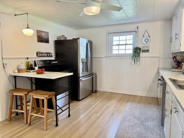 12 Wellington St, Buckland, MA 01370 - kitchen featuring appliances with stainless steel finishes, wainscoting, light wood finished floors, ceiling fan, and white cabinets