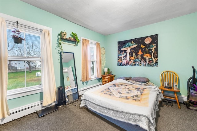 carpeted bedroom featuring a textured ceiling, a baseboard heating unit, and multiple windows
