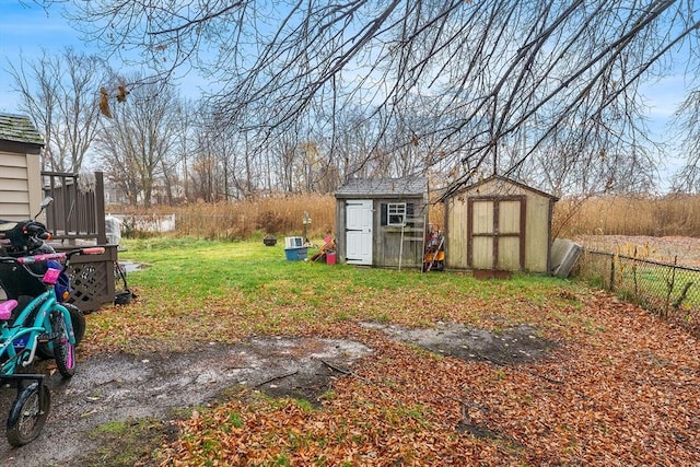 view of yard with fence, an outdoor structure, and a storage unit