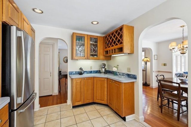 kitchen featuring glass insert cabinets, freestanding refrigerator, light countertops, and recessed lighting