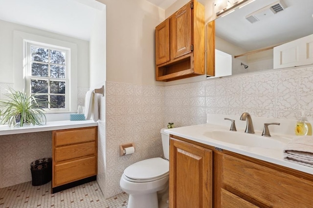 bathroom featuring toilet, vanity, visible vents, tile walls, and a shower