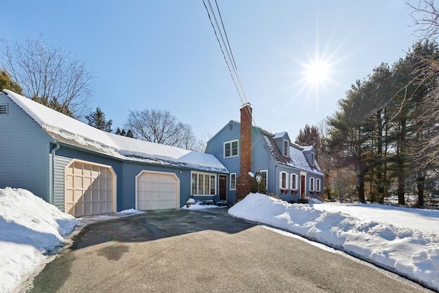 dutch colonial with driveway, a chimney, an attached garage, and a gambrel roof