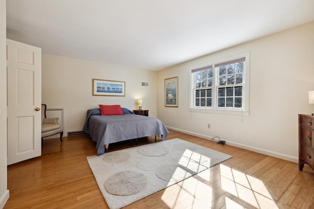 bedroom with light wood-style floors, visible vents, and baseboards