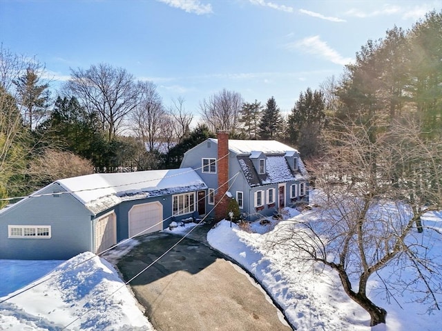 dutch colonial featuring driveway, a chimney, and an attached garage