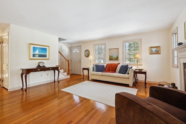 living area with light wood-type flooring, stairway, baseboards, and a tile fireplace