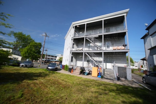 rear view of house featuring stairs and a lawn