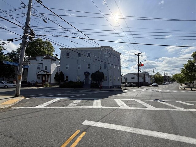 view of asphalt street featuring street lighting, curbs, and sidewalks