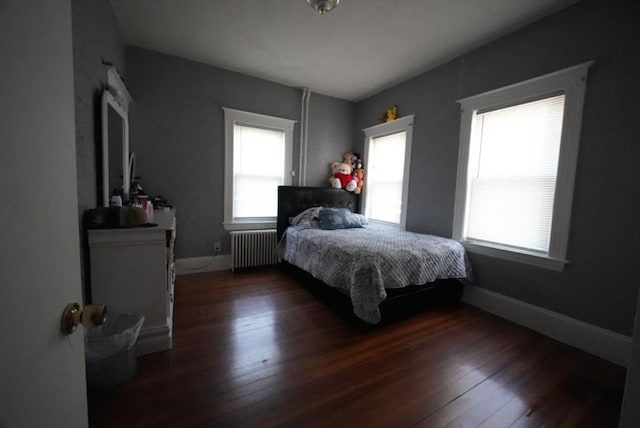 bedroom featuring radiator heating unit, wood finished floors, and baseboards