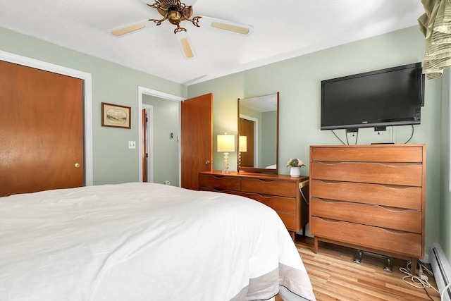 bedroom with light wood-style flooring, ceiling fan, and baseboard heating
