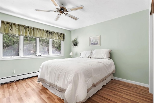 bedroom with wood finished floors, a baseboard radiator, baseboards, and ceiling fan