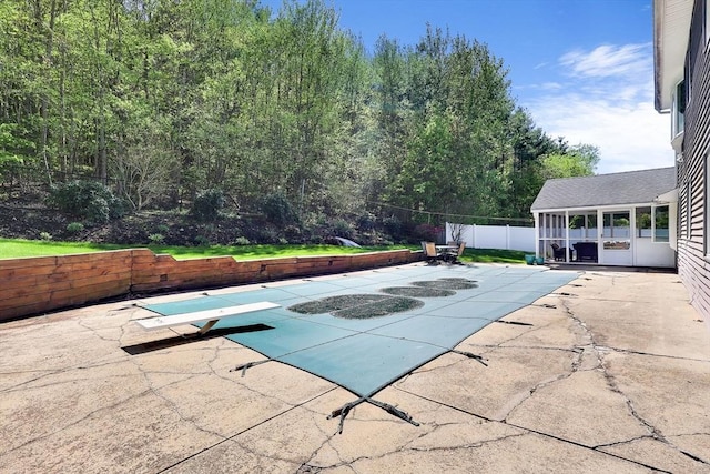 view of pool with a patio area, a diving board, and fence