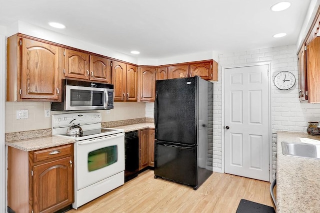 kitchen featuring electric stove, freestanding refrigerator, stainless steel microwave, light countertops, and backsplash