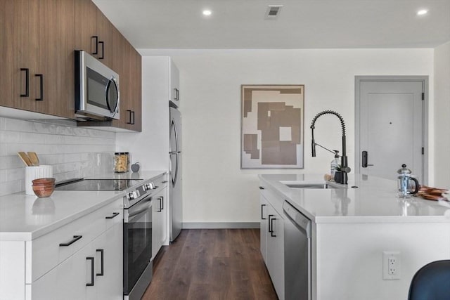 kitchen with visible vents, light countertops, appliances with stainless steel finishes, dark wood-style floors, and a sink