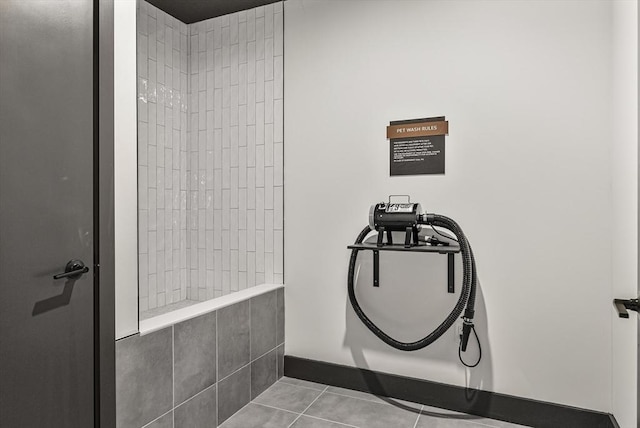 bathroom with baseboards, a tile shower, and tile patterned flooring