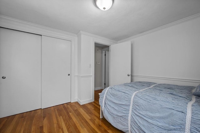 bedroom featuring hardwood / wood-style flooring, ornamental molding, and a closet