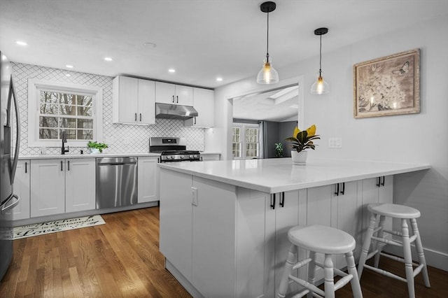 kitchen featuring pendant lighting, a breakfast bar area, white cabinetry, stainless steel appliances, and kitchen peninsula