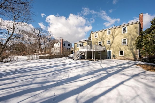 snow covered rear of property with a wooden deck