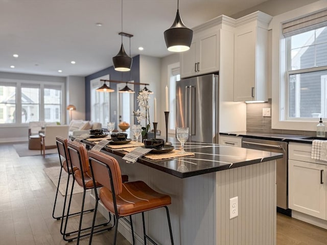 kitchen featuring white cabinets, hanging light fixtures, and appliances with stainless steel finishes