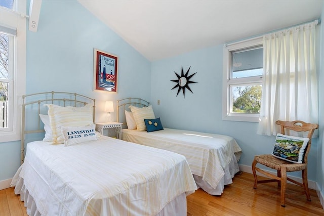 bedroom with light wood-style flooring, vaulted ceiling, and baseboards