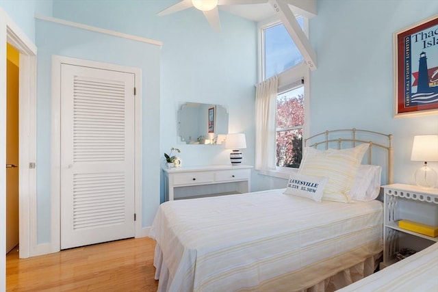 bedroom featuring light wood finished floors, a high ceiling, a closet, and a ceiling fan