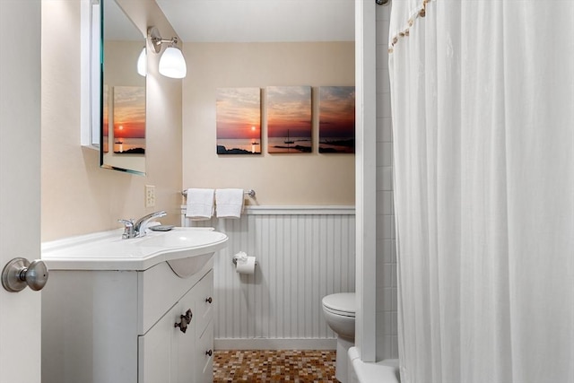 bathroom featuring toilet, vanity, and wainscoting