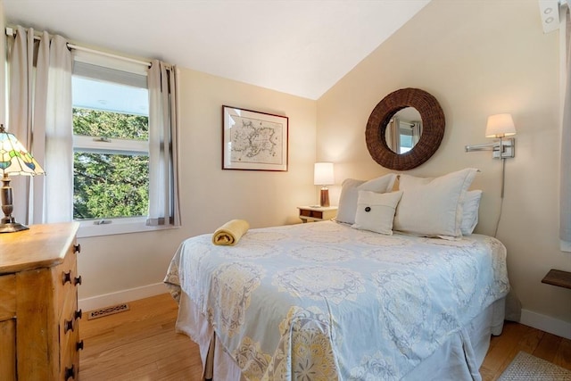 bedroom featuring light wood finished floors, baseboards, and lofted ceiling