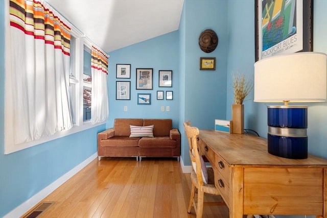 living area with baseboards, lofted ceiling, and hardwood / wood-style flooring