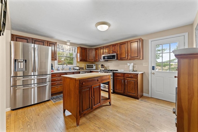 31 Wight St, Waltham, MA 02452 - kitchen with a kitchen breakfast bar, a kitchen island, a sink, stainless steel appliances, and light wood-style flooring