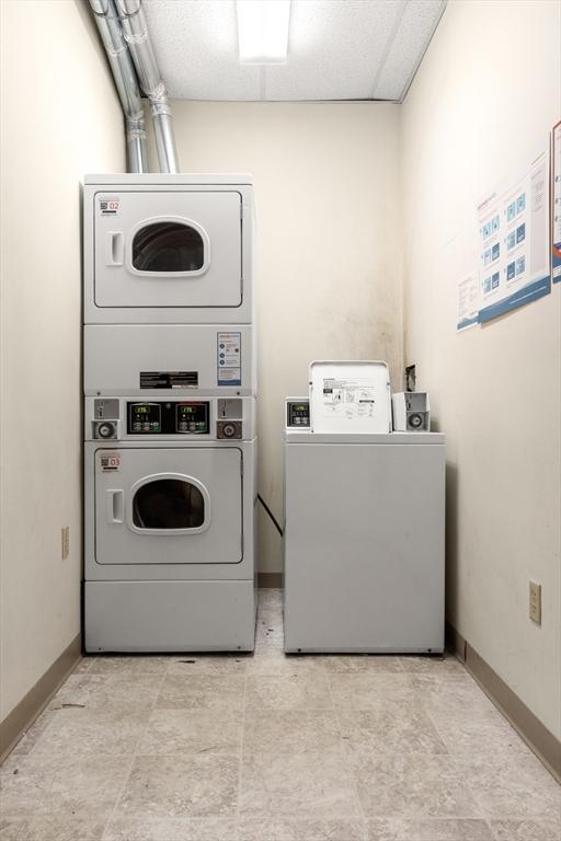 common laundry area with independent washer and dryer, stacked washing maching and dryer, and baseboards