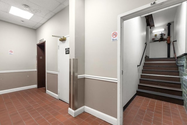 stairs with baseboards and a paneled ceiling