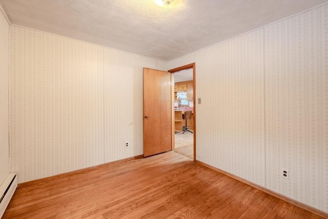 spare room with a baseboard heating unit and wood-type flooring