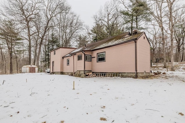 snow covered back of property with a storage shed