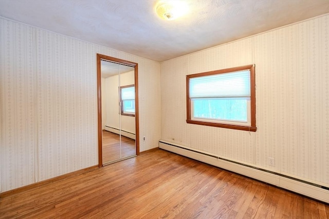 spare room with baseboard heating and wood-type flooring