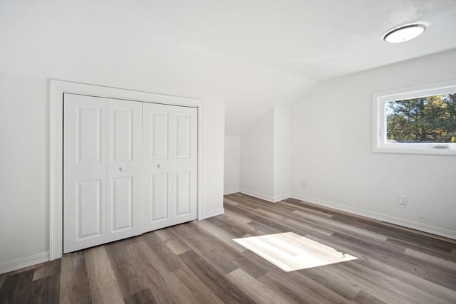 unfurnished bedroom featuring hardwood / wood-style floors, a closet, and vaulted ceiling